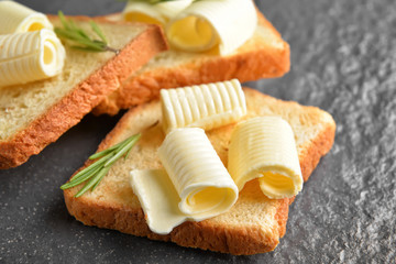 Toasted bread with butter and rosemary on dark background