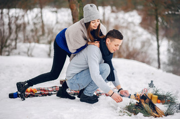 Couple in a winter forest. Beautiful girl in a blue sweater. Boy and girl near bonfire