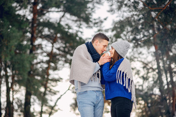 Couple in a winter forest. Beautiful girl in a blue sweater.