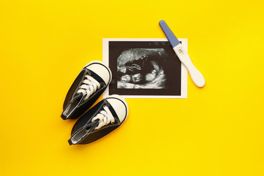 Pregnancy test, sonogram image and baby booties on color background