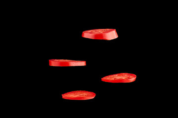 Creative concept with flying tomato. Sliced red tomato isolated on black background. Levity vegetable floating in the air