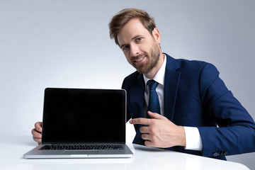 Confident businessman pointing to his laptop and smiling