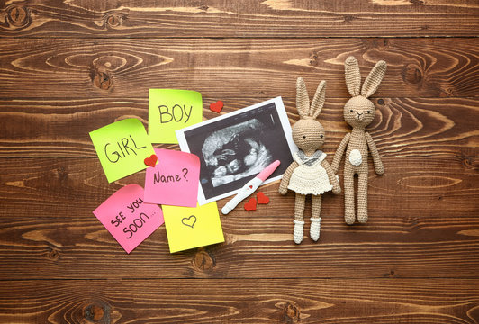 Pregnancy test, sonogram image and toys on wooden background