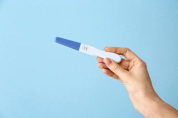 Female hand with pregnancy test on color background - obrazy, fototapety, plakaty
