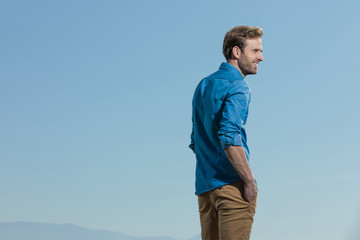 casual man standing with hands in pocket looking ahead happy