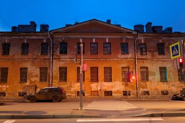 pedestrian crossing in front of an old house with showered plaster at dusk