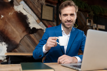 Positive businessman smiling and holding a cup of coffee