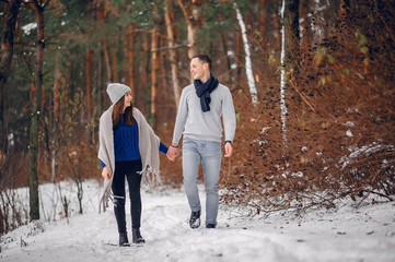Couple in a winter forest. Beautiful girl in a blue sweater.