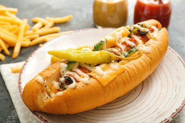 Plate with tasty hot dog on table