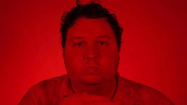 Young man with humorous funny face expressions isolated on a red lighting