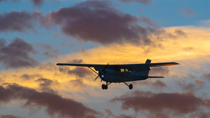 Fototapeta na wymiar Shot of a silhouetted, unidentifiable private aircraft on final for landing as the sun sets.