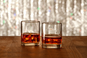 Whiskey with ice or brandy in a glass on a rustic table and gray background. Whiskey with ice in a glass. Whiskey or cognac in a glass. Selective focus.