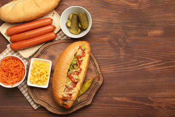Tasty hot dog and ingredients on wooden background