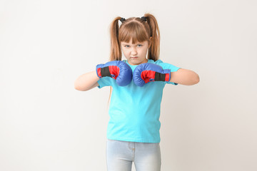 Little girl in boxing gloves on light background. Concept of feminism