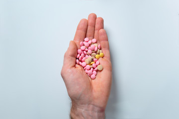 full palm holding out multi-colored, close-up, pills on white background