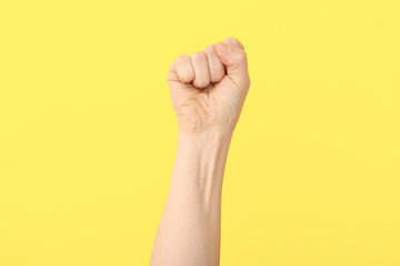 Hand of woman with clenched fist on color background