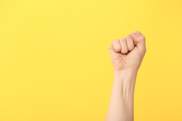 Hand of woman with clenched fist on color background