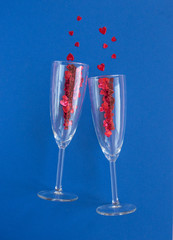 Valentines day composition. Flat lay with two champagne glasses with red hearts  on classic blue background. Top view. Valentine day, wedding, birthday concept. Greeting card