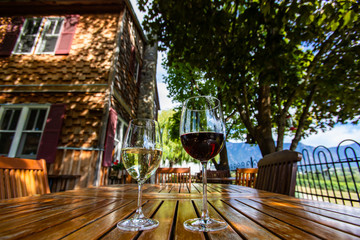 two different glasses sizes and wines, red and white wine on wooden table close up selective focus, farmhouse backyard patio furniture Okanagan Valley