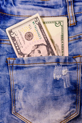 American five dollar banknotes in a pocket of blue jeans