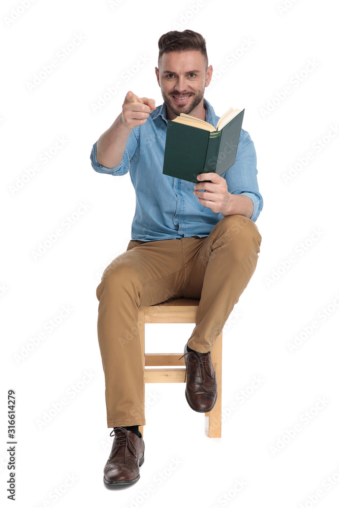 Sticker young casual man holding book and pointing finger