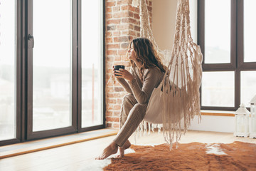 Woman wearing cashmere nightwear relaxing in cabin near fireplace - obrazy, fototapety, plakaty