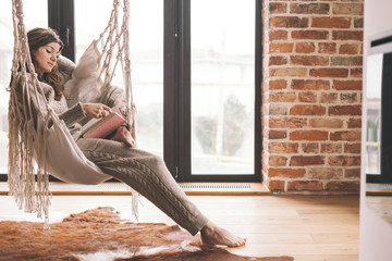 Woman wearing cashmere nightwear relaxing in cabin near fireplace