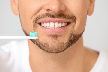 Obraz premium Handsome man with tooth brush on grey background, closeup