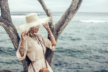 Boho model wearing dress and straw hat on the beach