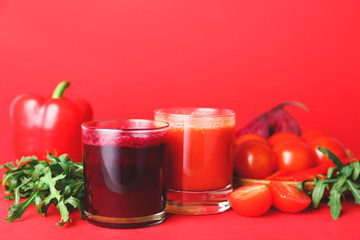 Glasses of fresh vegetable juices on color background