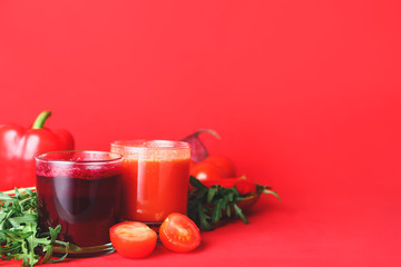 Glasses of fresh vegetable juices on color background