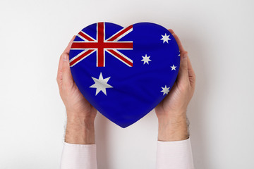 Flag of Australia on a heart shaped box in a male hands. White background