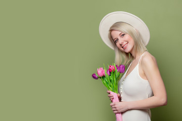 Beautiful blonde girl in white hat and dress with tulips