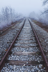 Railroad tracks leading into the unknown, surrounded by winter scenery