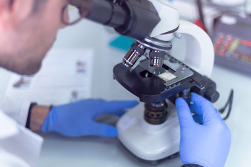 Young male scientist looking through a microscope in a laboratory doing research, microbiological analysis, medicine.