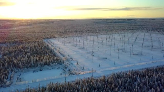 Aerial, pan, drone shot, of the HAARP antenna array, in middle of Alaskan woodlands, at sunset, on a sunny, winter evening, in Gakona, Alaska, USA