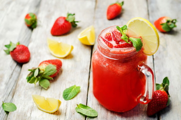 strawberry lemonade with fresh strawberries on a wood background