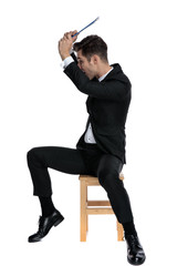 young elegant man in tuxedo defending himself with clipboard