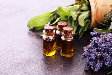 Fresh herbs from the garden and the different types of oils for massage and aromatherapy on table with lavender
