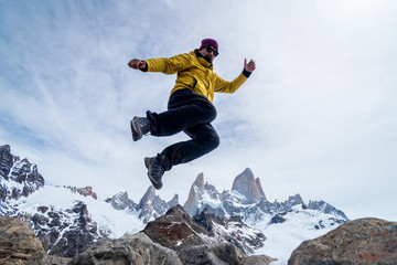 A hiker man jumping on the base of Fitz Roy Mountain in Patagonia, Argentina