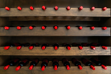 lines of wine bottles with a red seal, Stored on a wooden rack, tasting room wines display, tasting...