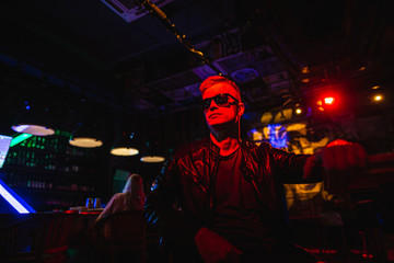 Fototapeta na wymiar Handsome man in leather jacket with sunglasses and neon lights.