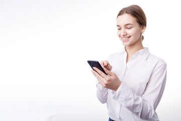 Smiling enthusiastic businesswoman in white blouse texting via smartphone isolated white background copyspace