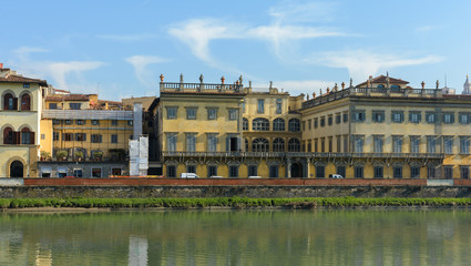 Arno River and the old promenade in Florence. Hazel houses with red roofs in Florence. Houses are reflected in the water.