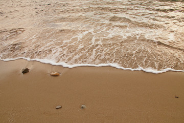 Fototapeta na wymiar Sea water caressing the orange sand