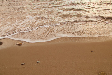 Fototapeta na wymiar Sea water caressing the orange sand