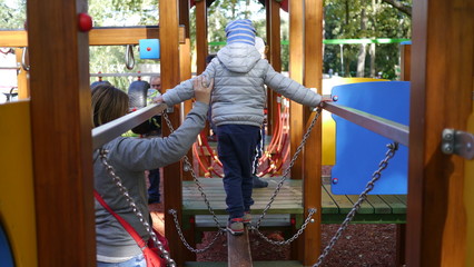 Chłopiec bawi sie na placu zabaw. Skacze na trampolinie i wspina się . © Marcin
