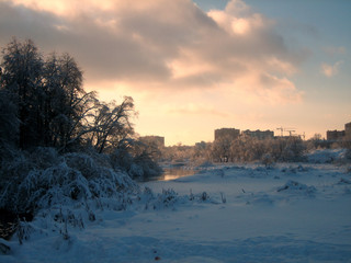 In winter, the city Park, trees and shrubs are buried in snow at sunset on a clear frosty day. The...