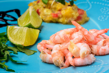 On a blue plate is an Asian national dish. Freshly prepared shrimps with mango chutney sauce with hot pepper.