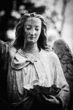 Black and white image of ancient statue of an angel of death as symbol of end of human life.